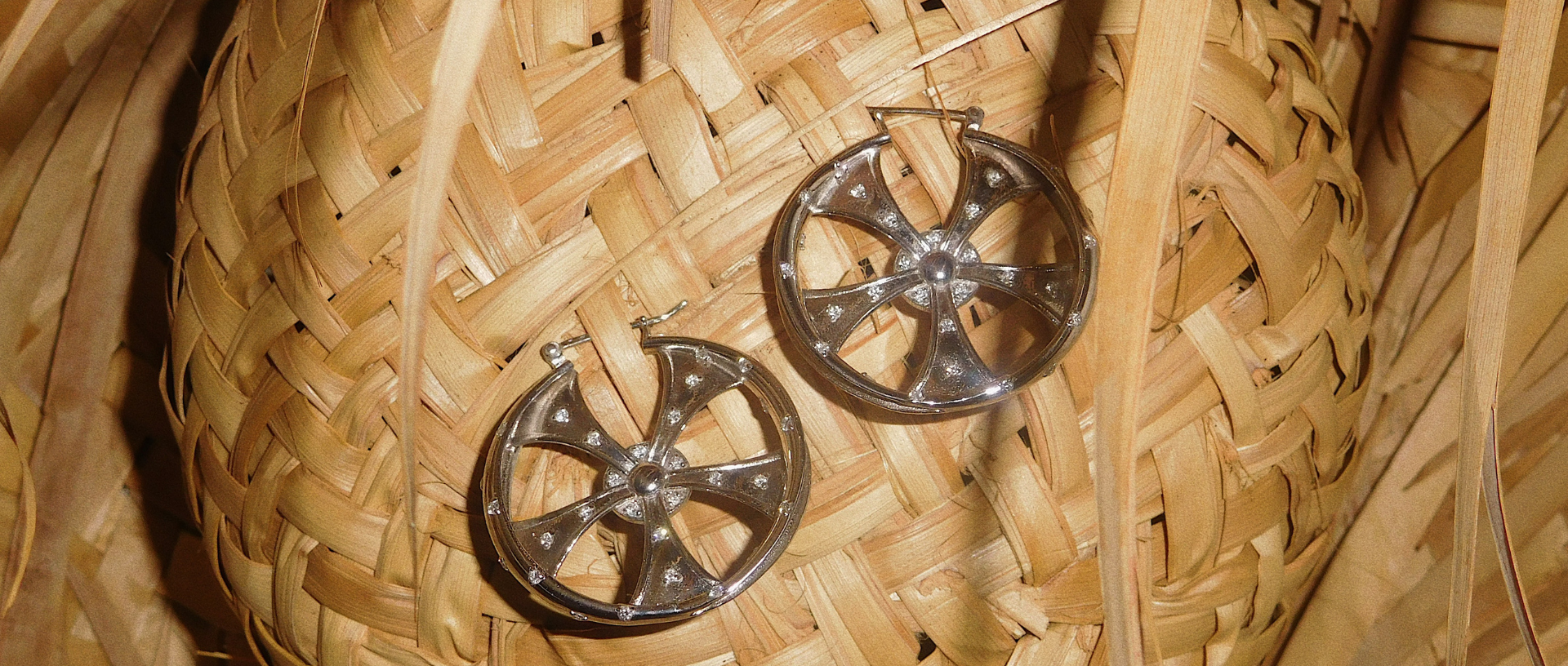 Metal earrings on a woven straw surface